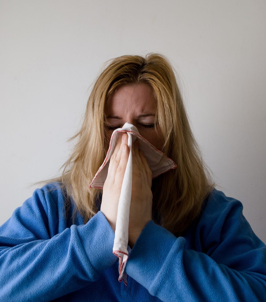 woman sneezing and covering mouth